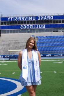 Sara Wilson standing in Drake stadium with graduation gear on